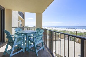 A balcony with a table and chairs, overlooking a beach. - Phoenix Iii 3013 1 Bedroom Condo (Orange Beach)