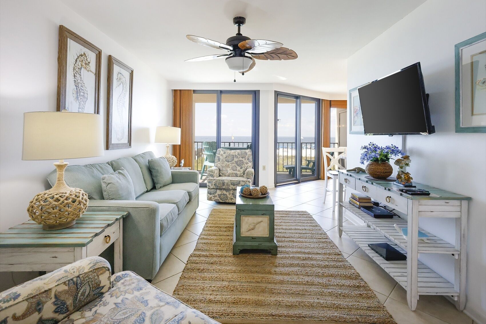 A living room with a sofa, a coffee table, a TV, and a ceiling fan.