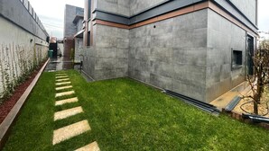 A modern building with a flat roof, a paved courtyard, and a small tree. - 4-bedroom house in lovely İstanbul with forest view.Nearest Istanbul Airport. (Bolluca)