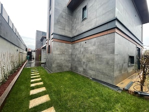 A modern building with a flat roof, a paved courtyard, and a small tree. - 4-bedroom house in lovely İstanbul with forest view.Nearest Istanbul Airport. (Bolluca)