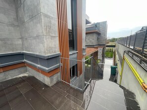 Ein modernes Gebäude mit einer Betonfassade, einem Metallgeländer und einer Treppe, die zu einer niedrigeren Ebene führt.