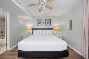 A bedroom with a bed, nightstands, lamps, a ceiling fan, and framed pictures on the wall. - Phoenix Iii 3023 1 Bedroom Condo (Orange Beach)