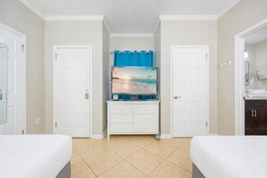 A hotel room with two beds, a TV on a dresser, and a bathroom visible through an open door. - Phoenix Vii 71506 2 Bedroom Condo (Orange Beach)