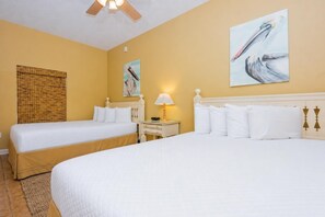 A hotel room with two beds, a bedside table with a lamp, and artwork on the walls. - Phoenix Vii 7012 3 Bedroom Condo (Orange Beach)