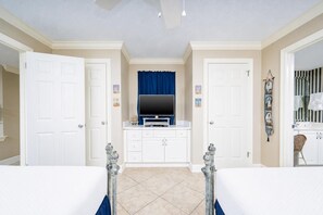 A room with a television on a white cabinet, a blue curtain, and a white door. - Phoenix Vii 7309 2 Bedroom Condo (Orange Beach)