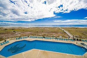 A pool with a unique design, surrounded by lounge chairs and a boardwalk leading to the beach. - Phoenix Vii 7309 2 Bedroom Condo (Orange Beach)