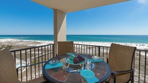 A balcony with a table set for dining, overlooking a beach and ocean. - Phoenix Vii 7813 2 Bedroom Condo (Orange Beach)
