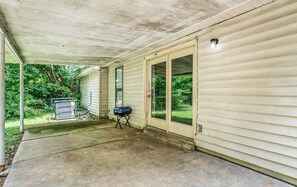 A covered porch with a grill, a utility box, and a door leading to a green yard. - Near Dining & MEM - Hickory Hill Home (Memphis)