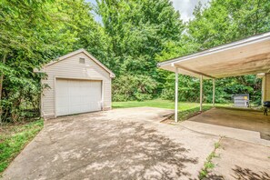 A garage with a covered porch, surrounded by lush greenery. - Spacious Memphis Retreat | Sleeps 12 | Near MEM (Memphis)