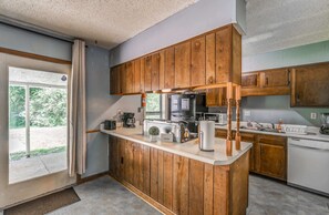 A kitchen with wooden cabinets, a countertop, a coffee maker, a toaster, and a dishwasher. - Spacious Memphis Retreat | Sleeps 12 | Near MEM (Memphis)