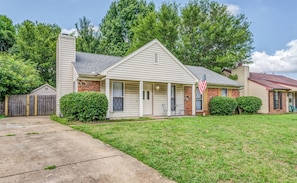 A single-story house with a front porch, a brick section, and a flag. - Spacious Memphis Retreat | Sleeps 12 | Near MEM (Memphis)