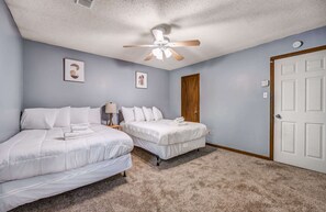 A bedroom with two beds, a ceiling fan, and a door. - Spacious Memphis Retreat | Sleeps 12 | Near MEM (Memphis)