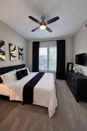 A bedroom with a bed, a ceiling fan, a dresser, and a TV. - Luxury 2BR • King Suite • Minutes to PGA, Universal & The Star (Frisco)