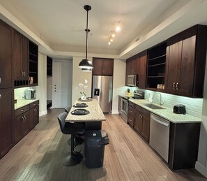 Una cocina moderna con armarios de madera oscura, electrodomésticos de acero inoxidable y una isla central con taburetes de bar.