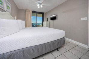 Une chambre d’hôtel avec un grand lit, un ventilateur de plafond, une télévision et une vue sur la ville.