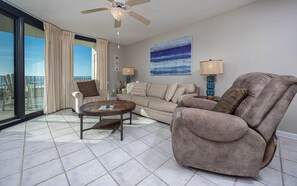 A living room with a sofa, armchair, coffee table, and a ceiling fan. - Phoenix Vii 7306 2 Bedroom Condo (Orange Beach)