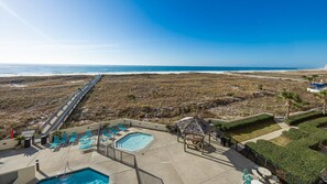 Un espace piscine avec des chaises longues, une petite piscine et une vue sur la plage.