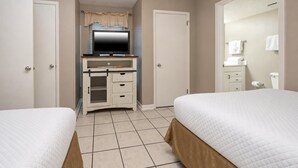 A hotel room with two beds, a television, a desk, and a bathroom. - Phoenix Vii 7306 2 Bedroom Condo (Orange Beach)