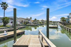 A marina with wooden docks, a clear sky, and residential buildings in the background. - High Cotton: Inlet Views, Private Dock, Pool & Easy Beach Access (Murrells Inlet)