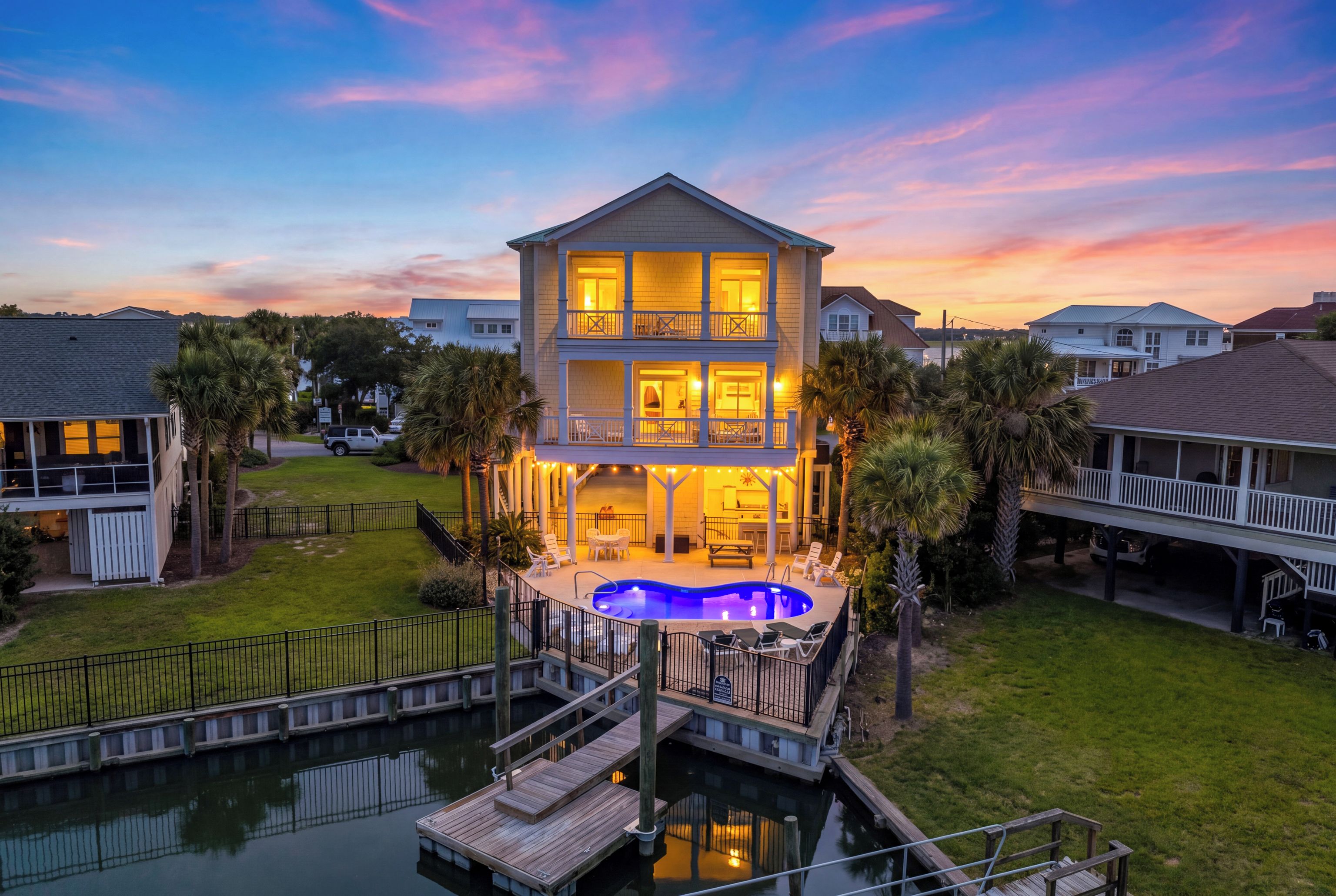 A two-story house with a swimming pool, deck, and dock.