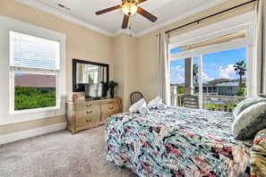 Ein Schlafzimmer mit einem großen Bett, einem Deckenventilator, einem Fernseher, einem Korbmöbel-Schrank und Blick ins Freie.