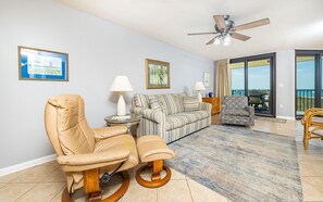 A living room with a sofa, a chair, a table with a lamp, and a ceiling fan. - Phoenix Vii 7202 1 Bedroom Condo (Orange Beach)