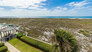 A coastal property with a paved walkway, beach access, and a small building with outdoor seating. - Phoenix Vii 7202 1 Bedroom Condo (Orange Beach)