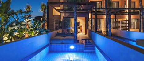 Un hotel moderno con piscina, zona de estar al aire libre y una entrada bien iluminada.