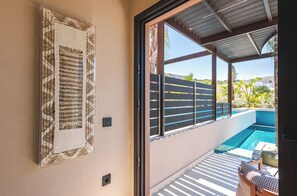 Una habitación con puerta corrediza de vidrio que da a una zona de piscina, un cuadro en la pared y techo con cubierta de metal.