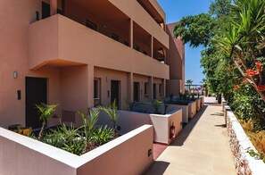 A multi-story hotel with balconies, a covered outdoor seating area, and a landscaped garden with tropical plants.