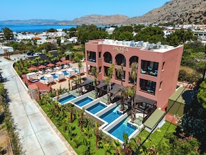 A hotel with a rooftop pool, multiple balconies, and a view of the sea.