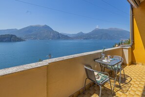 Ein Balkon mit Tisch und Stühlen mit Blick auf einen See, in der Ferne Berge.