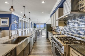 A modern kitchen with stainless steel appliances, a tiled backsplash, and pendant lighting. - Lazy Daze: Oceanfront, Endless Coastal Views & Pool (Murrells Inlet)