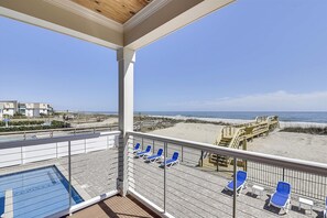 Ein Balkon mit Pool, Liegestühlen und Blick auf Strand und Meer.