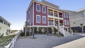 A multi-story residential building with a balcony, a staircase, and a paved driveway. - Lazy Daze: Oceanfront, Endless Coastal Views & Pool (Murrells Inlet)