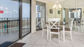 A dining area with a round table and white chairs, a balcony with a railing, and a view of the beach. - Phoenix Vii 7211 1 Bedroom Condo (Orange Beach)