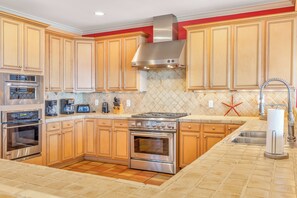 A kitchen with wooden cabinets, a stainless steel range hood, a built-in oven, a coffee maker, and a toaster. - Majestic Dream: Oceanfront, Pool, Hot Tub & Endless Coastal Days (Murrells Inlet)