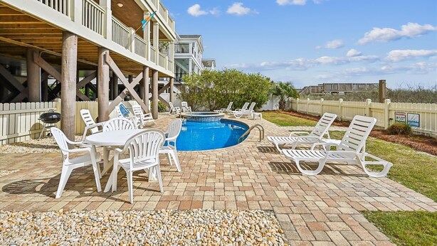 A pool area with lounge chairs and a barbecue grill. - Majestic Dream: Oceanfront, Pool, Hot Tub & Endless Coastal Days (Murrells Inlet)