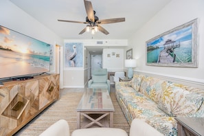 A living room with a television, a ceiling fan, a sofa, and a coffee table. - Phoenix Iii 3047 1 Bedroom Condo (Orange Beach)