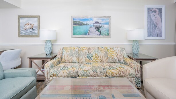 A living room with a sofa, two side tables, a lamp, and three framed artworks on the wall. - Phoenix Iii 3047 1 Bedroom Condo (Orange Beach)