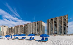 Ein Strandhotel mit mehreren Hochhäusern, Strandstühlen und Liegen.