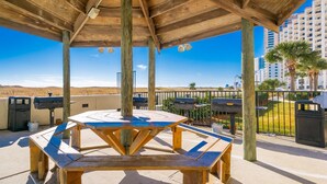 A covered outdoor area with a picnic table and barbecue grills. - Phoenix Vii 7602 1 Bedroom Condo (Orange Beach)