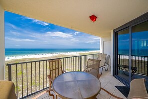 Ein Balkon mit Blick auf den Strand, einem runden Tisch und Stühlen.