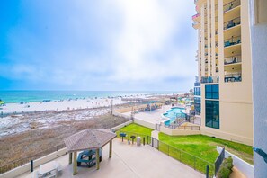 A balcony with a view of a beach, a pool area, and a building with multiple balconies. - Phoenix Iii 3022 1 Bedroom Condo (Orange Beach)