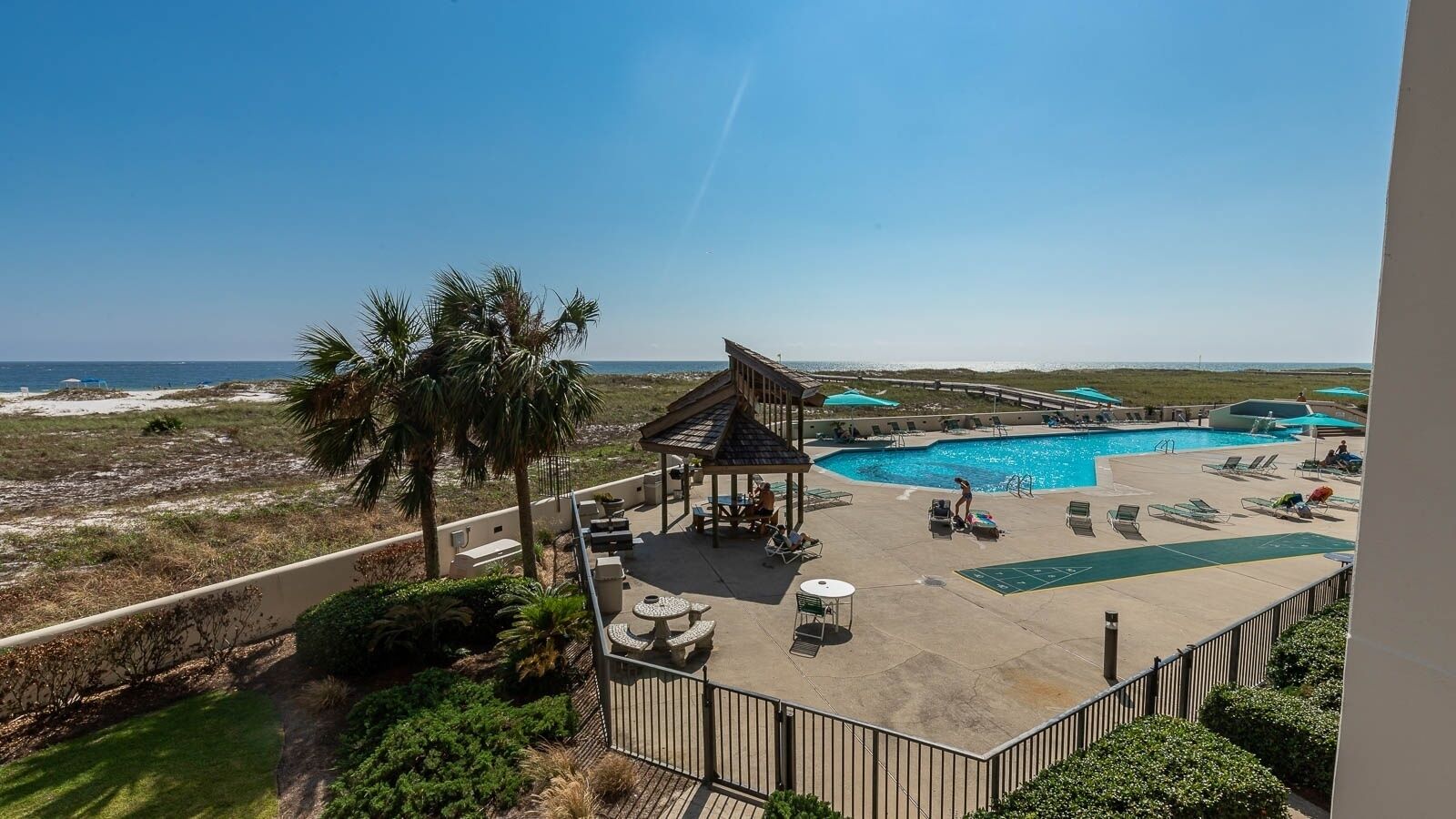 Un espace piscine avec des chaises longues, un gazebo et une vue sur l’océan.