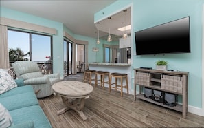 A modern living room with a sofa, a round coffee table, and a TV mounted on the wall. - Phoenix Vii 7114 1 Bedroom Condo (Orange Beach)