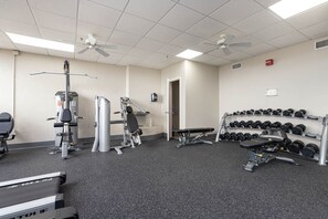 Ein Fitnessstudio mit Trainingsgeräten, Laufbändern und einer Hantelbank.