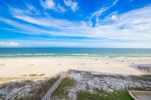 A beach with a wooden walkway leading to the water, a sandy beach, and a clear sky. - Phoenix Iii 3072 1 Bedroom Condo (Orange Beach)