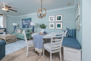 Ein Wohnzimmer mit einem runden Esstisch, weißen Stühlen, einem grünen Sofa und einer blauen Wand.