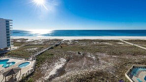 Ein Strandgrundstück mit Poolbereich, einem Steg und einem Gebäude mit Balkonen.